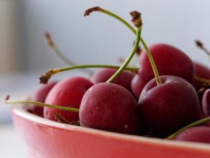 a zoomed in image of cherries in a red bowl