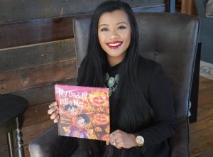 Thuba Nguyen holding a copy of her children's book, My Daddy Tells Me