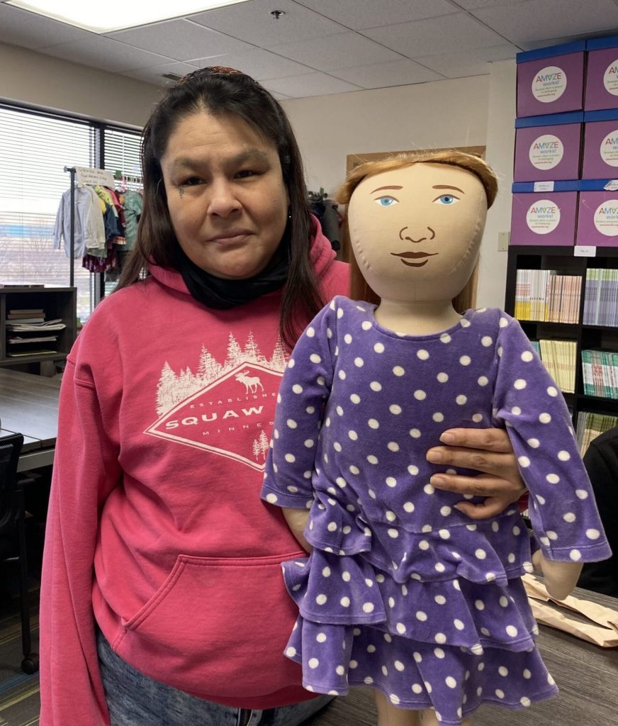 Jennifer Goggleye holding Persona Doll, Madison, who wears a purple polka dotted dress