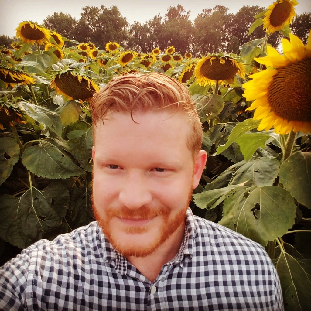 Ryan Boosinger smiling in a sunflower field