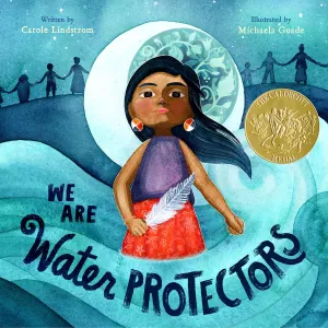 “We Are Water Protectors” book cover, written by Carole Windstrom and illustrated by Michaela Goade. An Ojibwe girl stands holding a feather in front of a moon and standing in water with silhouettes of people holding hands in the background.