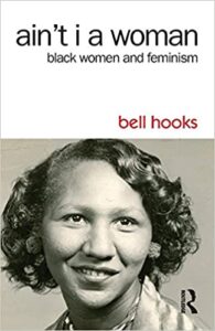Book cover for "Aint I a Woman: Black Women and Feminism" written by bell hooks. The cover features a sepia image of bell hooks's mother as a girl. She is smiling and has curly hair.