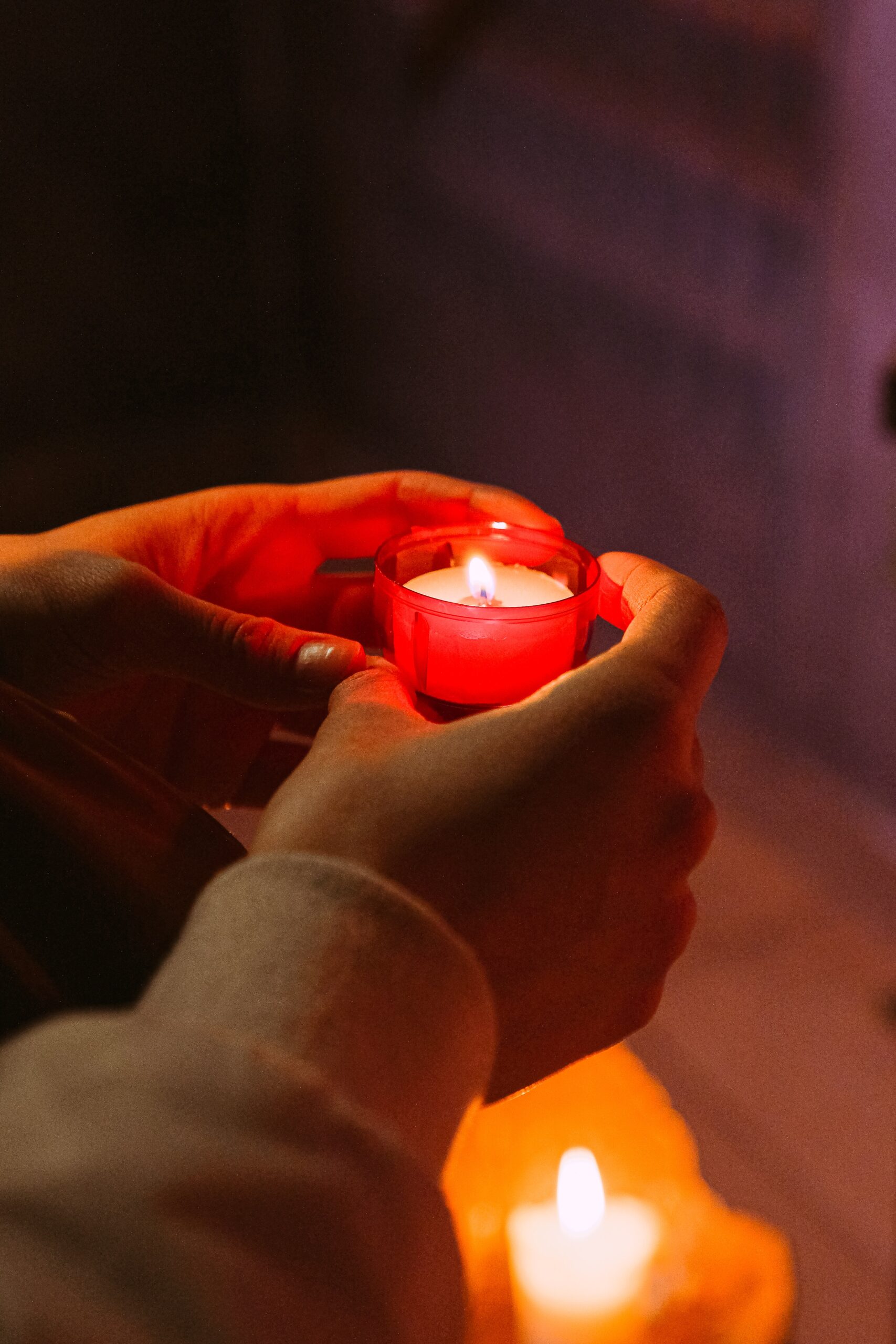 Two hands holding a small candle