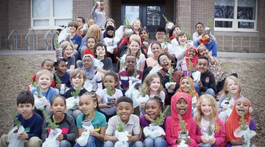 Rows of elementary school students holding their trees from Neighborhood Forest with big, big smiles!