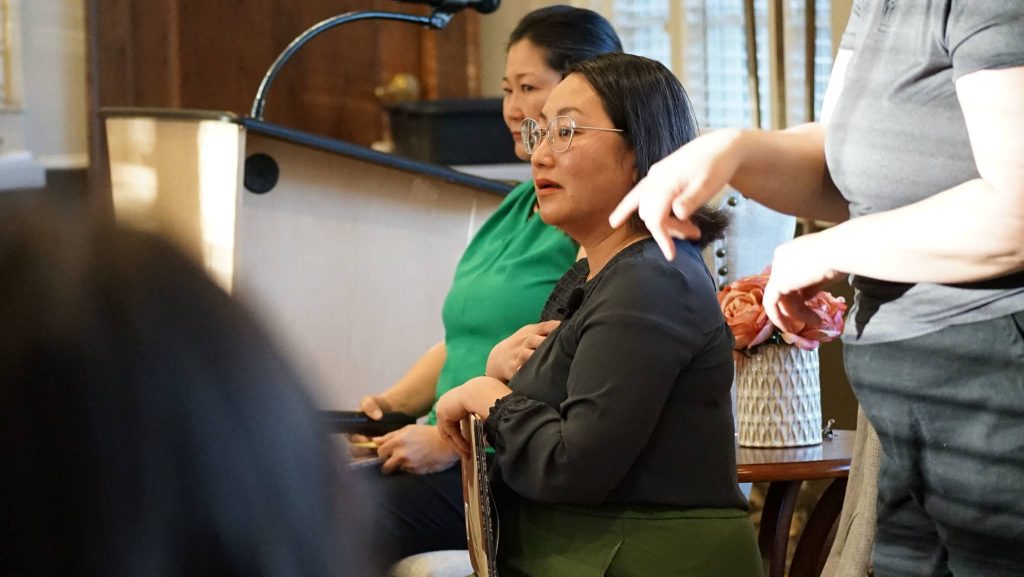Kao Kalia Yang Kao Kalia Yang holds a hand to her heart while sitting and holding a copy of her children's book