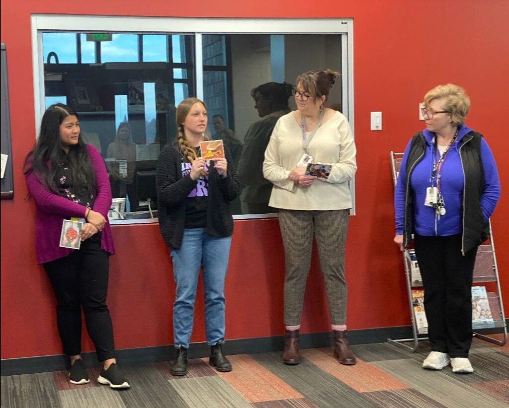 Four AmazeWorks Training Academy teachers standing against a red wall holding metaFox coaching cards. One teacher explains why she chose her card.