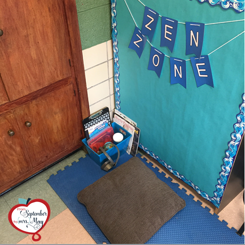 A classroom corner with a gray pillow and a blue basket filled with sensory tools sitting atop a blue mat on the floor. To the side, blue letters reading "Zen Zone" are posted on a bulletin board with blue construction paper and a blue border.