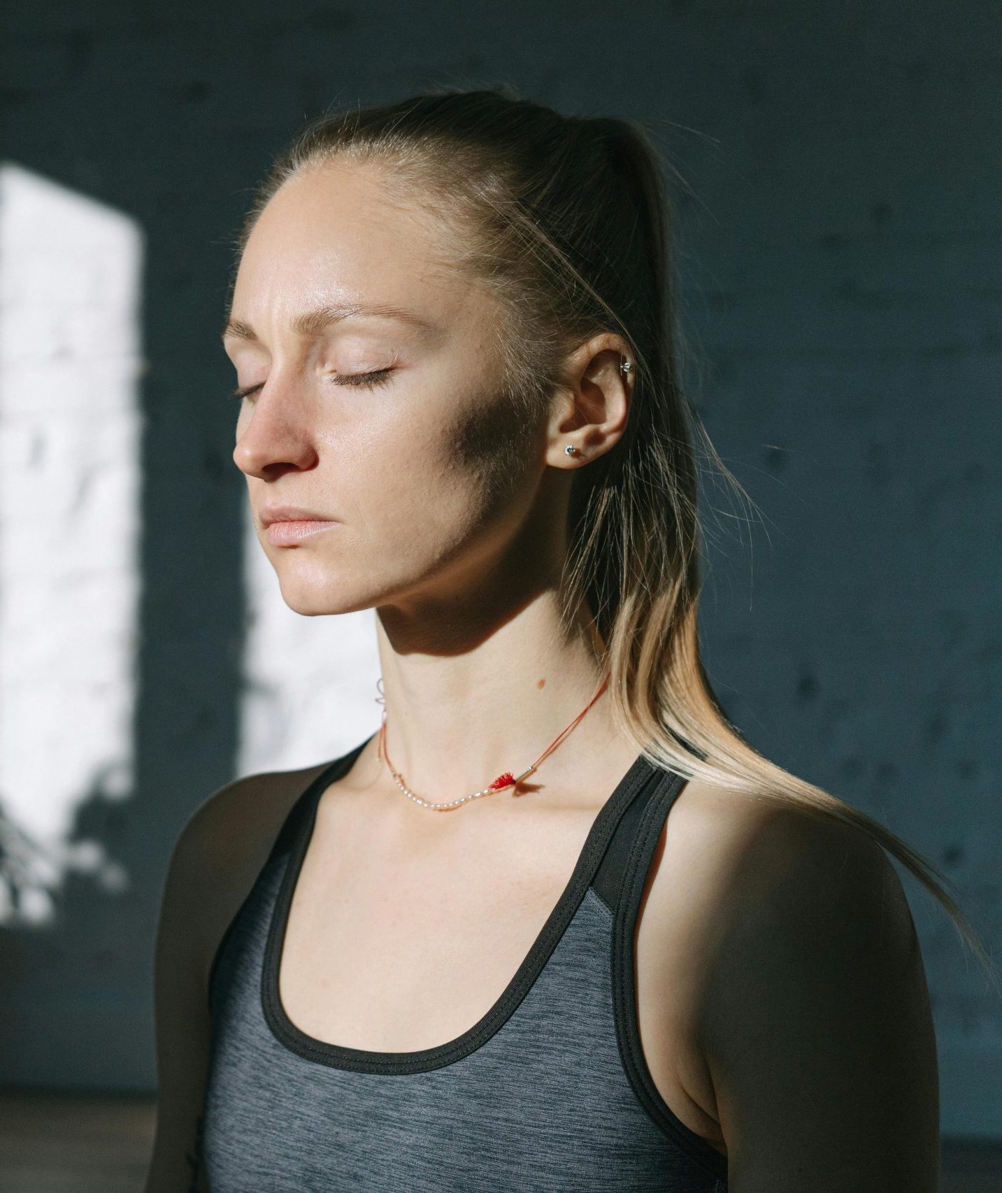 a White woman with blonde hair in a ponytail, taking a deep breath.