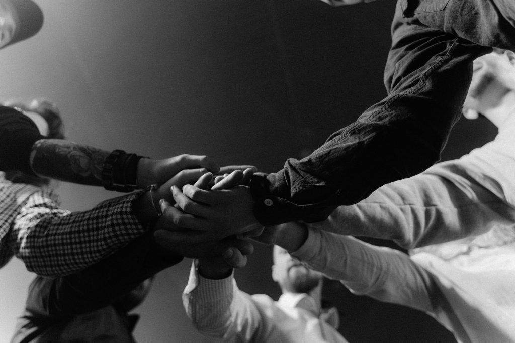 Seven arms outstretched to touch hands in the center of a circle