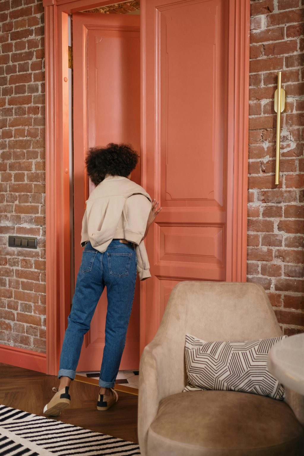 Woman opening a large coral door inside a brick building