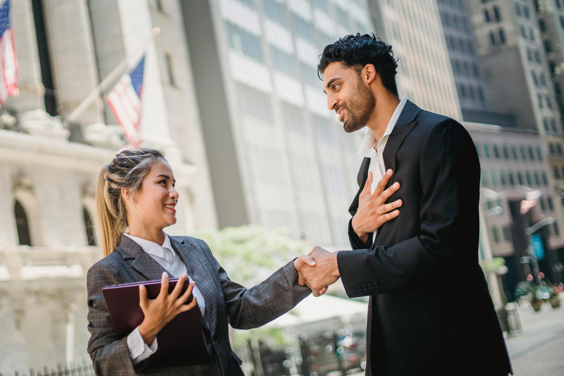 A woman and a man, both people of color, shaking hands while wearing business professional clothes