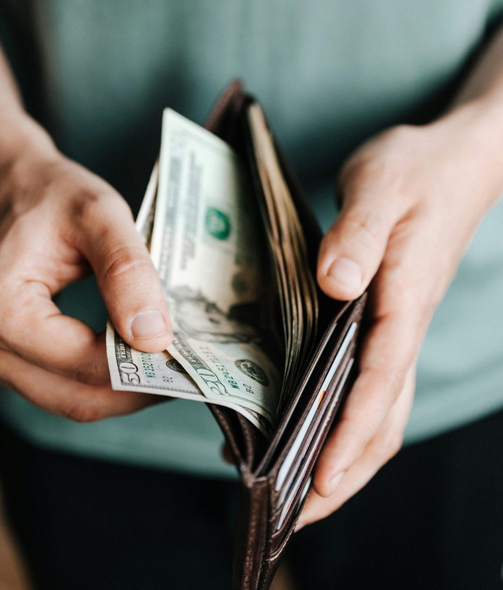 A closeup look of two hands looking through bills inside a wallet