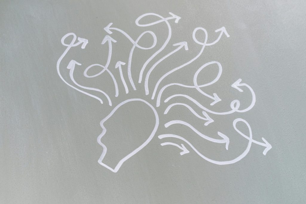 A drawn outline of a human head with lots of squiggly arrows coming out the top