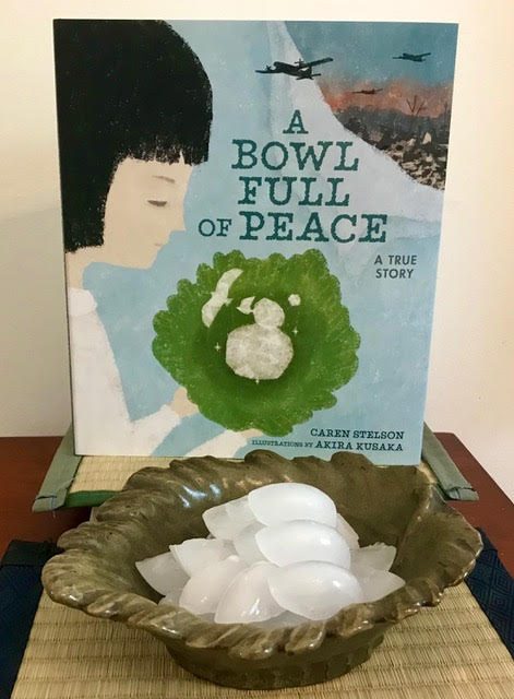 The picture book A Bowl Full of Peace by Caren Stelson is propped behind a green, leaf-shaped bowl full of ice chips