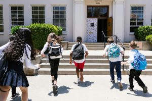 Five students running to enter school doors