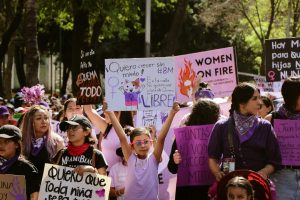 Women and girls marching holding up signs in Spanish and English, like "Women on Fire" and "Quiero crecer sin miedo"