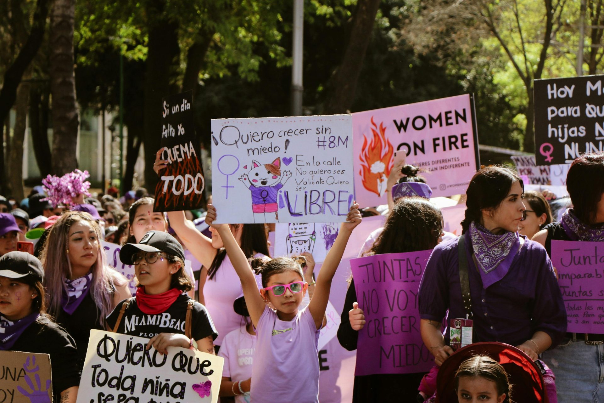 Women and girls marching holding up signs in Spanish and English, like "Women on Fire" and "Quiero crecer sin miedo"