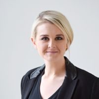 Headshot of Jenna Childs, a White woman with blonde hair pulled back into a ponytail. She is wearing a black shirt and blazer.