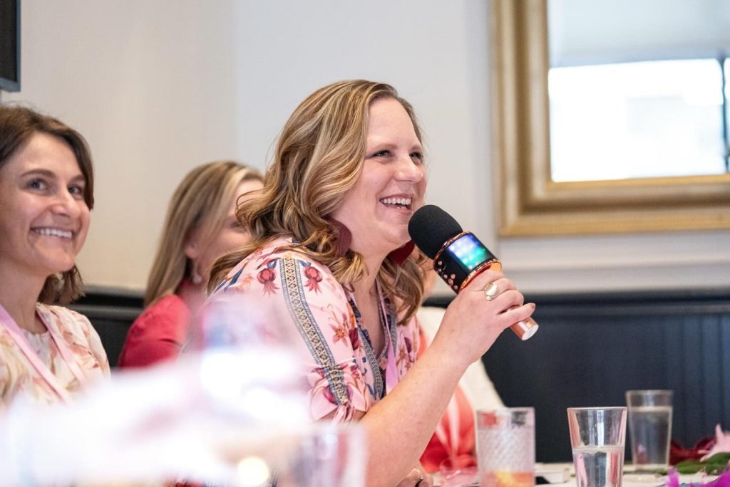 Mel Andersen smiling and speaking into a mic