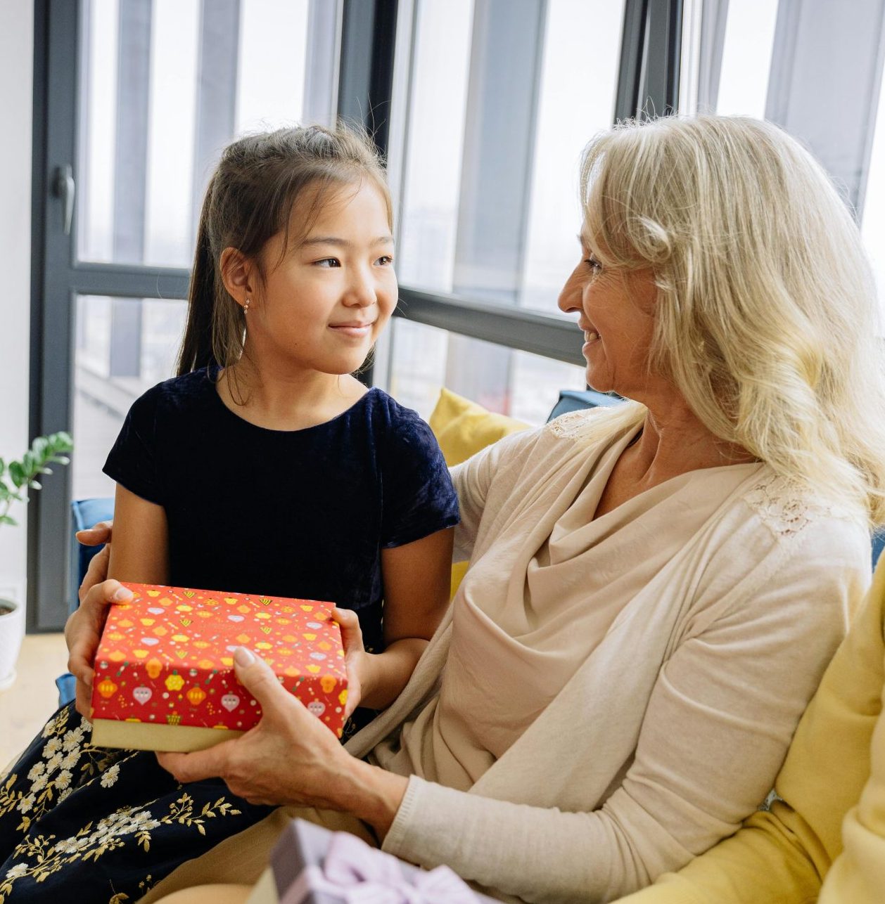 A grandmother gives a wrapped present to a child
