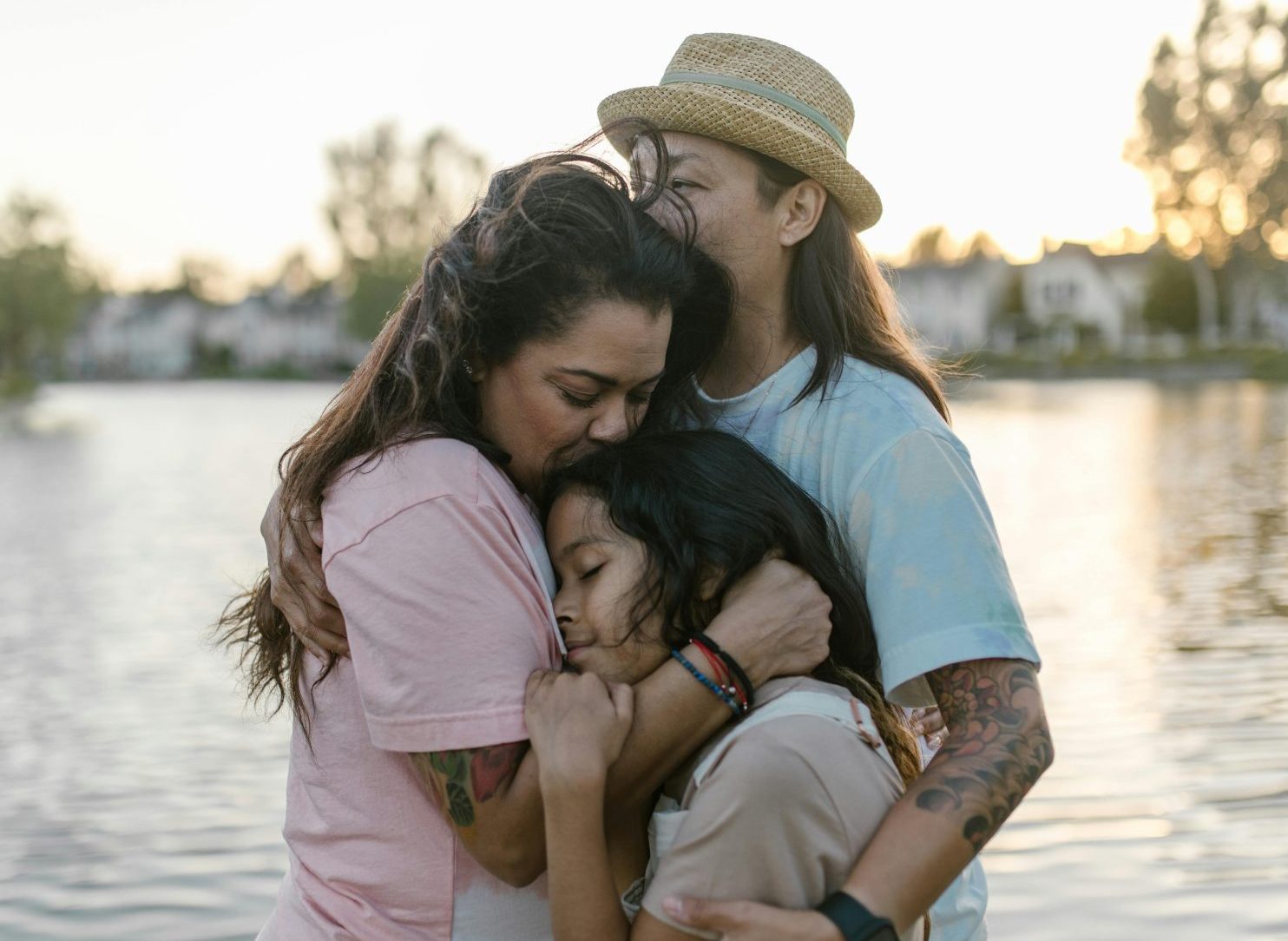 Two moms hug their daughter tight