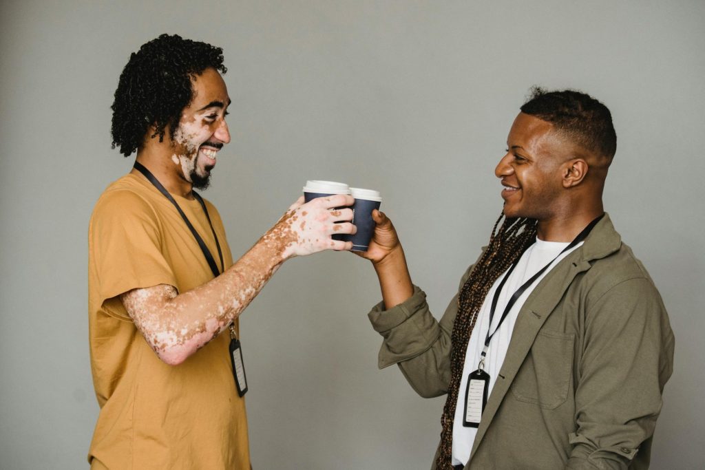 Two adults smile and cheers their coffee cups together